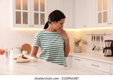 Young Woman Feeling Nausea While Seeing Food At Table In Kitchen