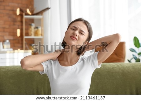 Young woman feeling neck pain at home