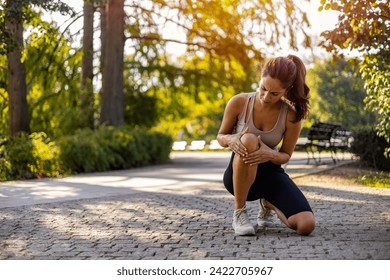 Young woman feeling pain in her knee. Woman runner got sports injury running on forest trail. Woman runner hold her sports injured knee.  - Powered by Shutterstock