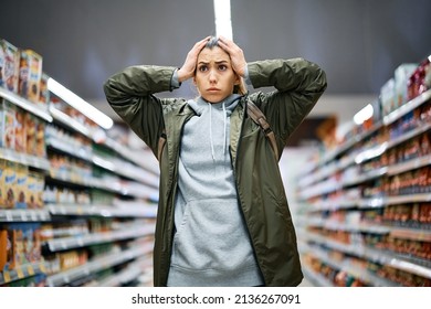 Young woman feeling shocked about rising food prices while standing among the aisle with groceries in supermarket.  - Powered by Shutterstock