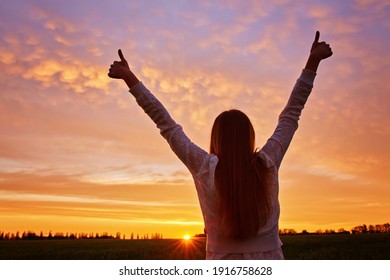 Young woman feeling victorious facing the beautiful sunset.
