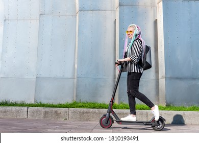 Young woman female adult tourist with colorful dreadlocks and modern electric scooter riding through city and urban scene avoiding traffic jam. Electric ecologic transport concept. - Powered by Shutterstock