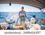 Young woman female captain stands at the helm and controls a sailboat during a journey by sea. High quality photo