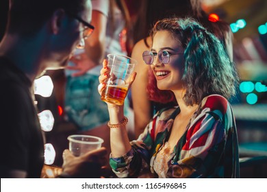 Young woman at the festival drinking beer with boyfriend