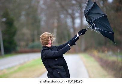 A young woman is fighting against the storm with her umbrella