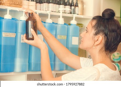 Young Woman Filling Natural Biodegradable Household Chemical Product From Container Dispenser In Zero Waste Plastic Free Store. Dispensers For Detergents, Shampoo, Soap, Conditioner.