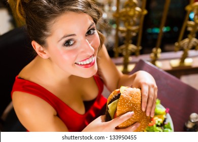 Young Woman In A Fine Dining Restaurant Eat A Hamburger, She Behaves Improperly