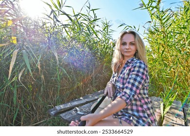 A young woman fishing in a lake and drinking beer. - Powered by Shutterstock