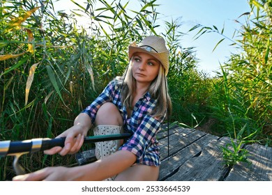 A young woman fishing in a lake and drinking beer. - Powered by Shutterstock