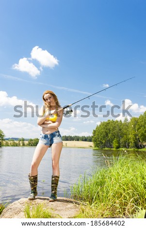 young woman fishing at pond in summer