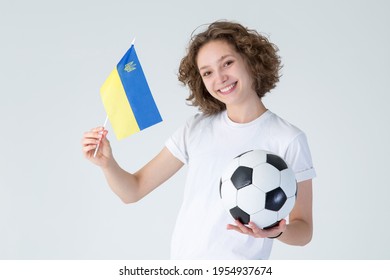 Young woman with flag of Ukraine and soccer ball in her hand, looks at camera, isolated on gray background. - Powered by Shutterstock