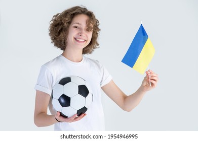 Young woman, with flag of Ukraine and soccer ball in hand, looks at camera, isolated on gray background. Ukrainian women's football. - Powered by Shutterstock