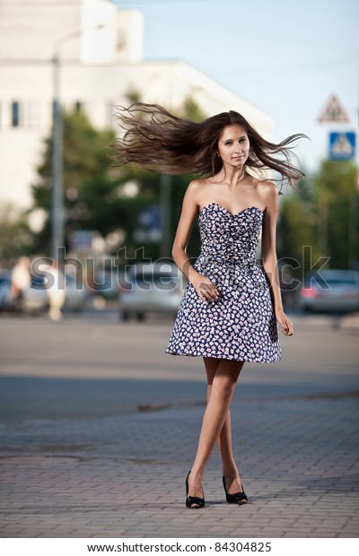 young\
woman with fluttering hair at the street in\
city