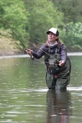 Young Woman Fly Fishing For Trout In A Clear River