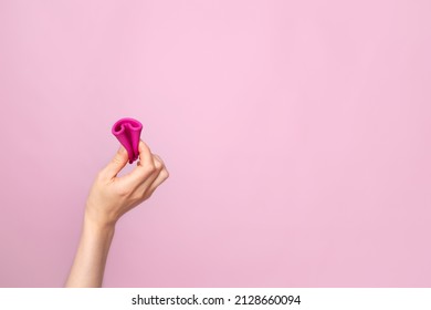  A Young Woman Folding A Pink Menstrual Cup In Her Hand. Pink Colored Background. Space For Text. Eco-friendly Silicone. Women's Health Cycle High Quality Photo