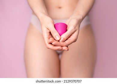 A Young Woman Folding A Pink Menstrual Cup In Her Hand. Pink Colored Background. Space For Text. Eco-friendly Silicone. Women's Health Cycle Mature Content. High Quality Photo