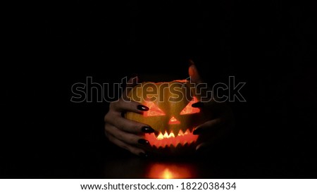 Young woman fooling around with a pumpkin. Halloween holiday. Gives creepy horns. Isolated black background.
