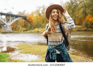 Young woman in a forest wearing a hat and backpack enjoys a peaceful day hiking among tall trees during autumn. Forest baths. Active lifestyle - Powered by Shutterstock