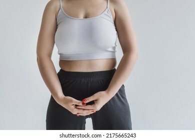 A Young Woman With Forms In A Light Top And Trousers On A Gray Background Holds Her Stomach With Her Hands. Pain During Menstruation. Plus Size Model No Face