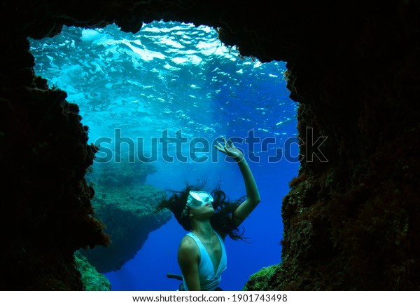 A young woman free diving apnea\
underwater cave.                                        \
