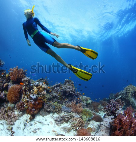 Young woman freediving in a sea over vivid coral reef