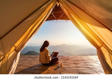 Young woman freelancer traveler working online using laptop and enjoying the beautiful nature landscape with mountain view at sunrise - Shutterstock ID 2143192569