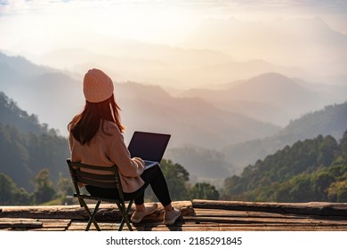 Young woman freelancer traveler working online using laptop and enjoying the beautiful nature landscape with mountain view at sunrise - Shutterstock ID 2185291845