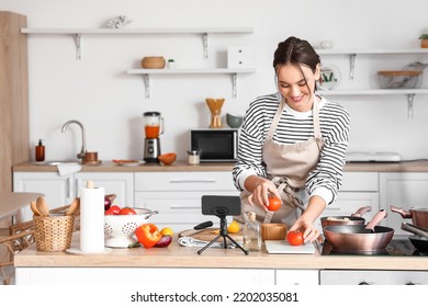 Young Woman With Fresh Tomatoes Following Cooking Video Tutorial In Kitchen