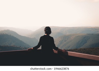 A young woman in front of massive mountains looking to the horizon during a sunny day wellness and liberty concept - Shutterstock ID 1946623876