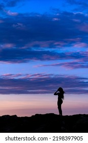 Young Woman Full Body Silhouette At Sunrise With Dramatic Blue Sky. 