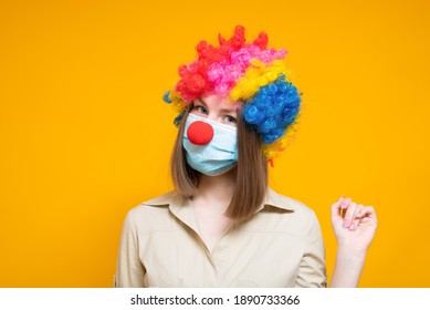 Young woman in a funny disguise in a medical mask on a colored background. Fools' day
