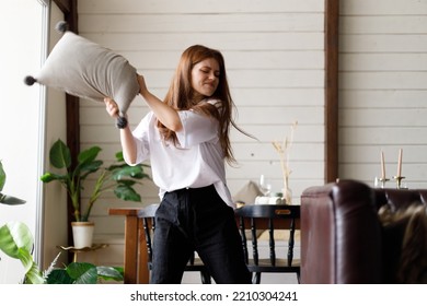 A young woman in fury kick a pillow at home. Conflict and negative emotions. - Shutterstock ID 2210304241