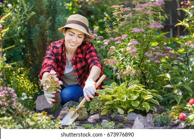 Young Woman Gardener Planting Flowers In The Garden. Hobby Concept