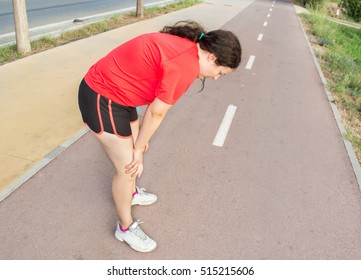 Young Woman Gasping For Air With Her Hands On Her Knees After A Run