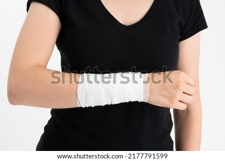 Young woman with gauze bandage wrapped around her injured hand. First aid, arm treatment after injury.