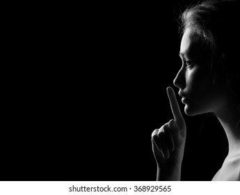 Young Woman Gesturing For Being Quiet, Shows Silence Sign In Dark Background With Copyspace, monochrome image