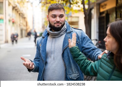 Young woman gesturing stop to young bearded man flirting with her on street.. - Shutterstock ID 1824538238