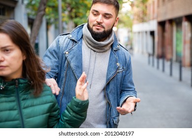 Young woman gesturing stop to young bearded man flirting with her on street.. - Shutterstock ID 2012040197