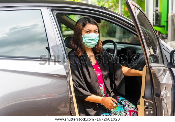 Young woman get out of the car\
using  face mask to prevent Corona virus or Covid-19 virus\
outbreak
