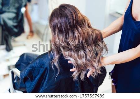 Young woman getting beautiful hairstyle in hair salon.