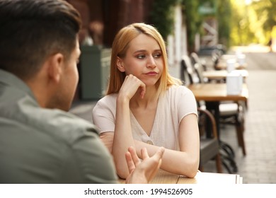 Young woman getting bored during first date with man at outdoor cafe