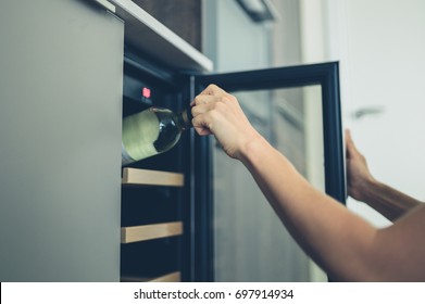 A Young Woman Is Getting A Bottle Of White Wine From Her Wine Cooler At Home