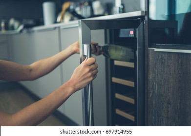 A Young Woman Is Getting A Bottle Of White Wine From Her Wine Cooler At Home