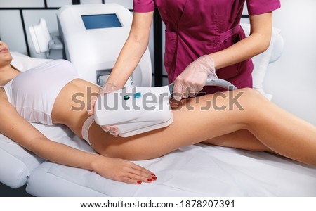 Young woman getting cryolipolyse treatment in cosmetic cabinet. Cool sculpting procedure for slimming thighs. Body Fat freezing technology