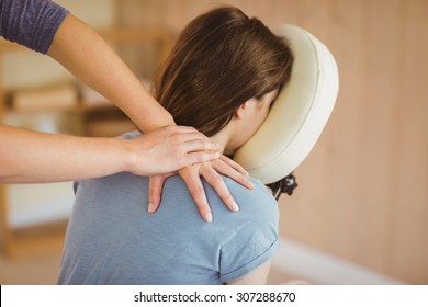 Young woman getting massage in chair in therapy room