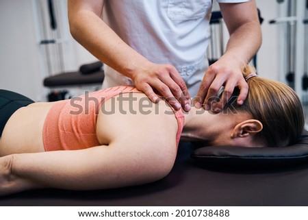 Young woman getting neck, head massage in therapy room. Masseur making chiropractic treatment