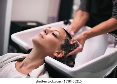 Young woman getting new hairstyle at professional hair styling saloon. Hairdresser is massaging her head.  - Shutterstock ID 1338483215