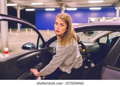 Young Woman Getting Out Of The Parked Car Opening Door Looking To The Camera Mad Angry Furious Pissed On The Parking In The City At Night