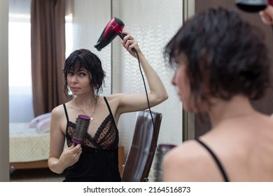 Young Woman Getting Ready For A Date, Drying Her Head With A Hair Dryer In Front Of A Mirror.