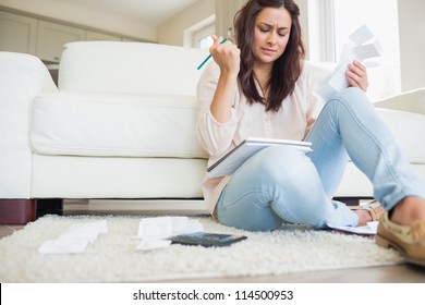 Young Woman Getting Stressed Over Bills On Floor Of Living Room